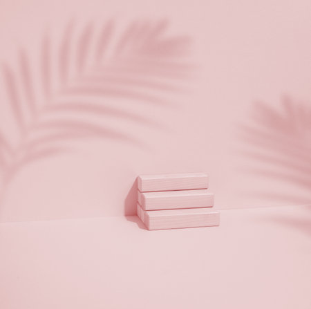Wooden cube on a pink background with a shadow from a palm leaf. Stage for product demonstration, cosmetics. Promotion and advertisingの写真素材