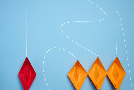 Paper boats on a blue background, representing the concept of competition in business, teamwork, and...