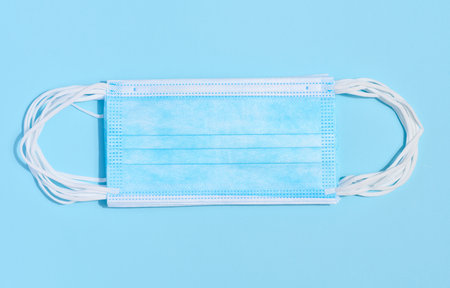 Disposable blue medical face mask against virus protection on a blue background, top view