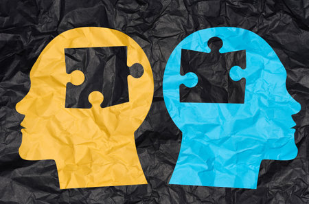 Two silhouettes of heads cut out from crumpled paper with puzzle pieces. Concept of similarity among people, finding a matchの写真素材