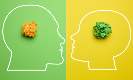 Two silhouettes of a man and a woman's heads with crumpled balls of paper inside, depicting the concept of mutual understanding and new ideasの写真素材
