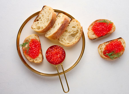 Sandwiches with red caviar and bread in a round plate on a white table, top viewの写真素材