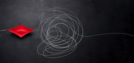 A red paper boat and a tangled trajectory drawn in chalk. The concept of difficult decisions, a long...