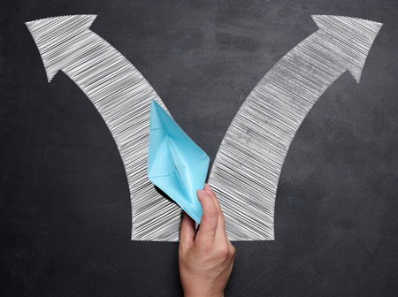 Hand holding a blue paper boat, concept of finding solutions, choosing direction of movementの写真素材