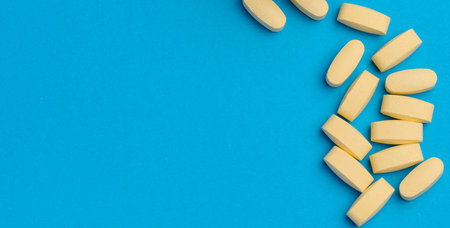 Yellow oval tablets on a blue background, top view. Copy spaceの写真素材