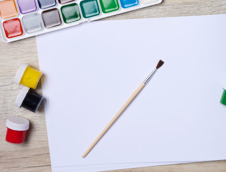 Open sketchbook with blank white sheets and acrylic paints, top viewの写真素材