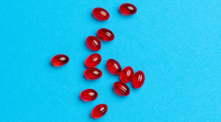Orange capsules with fish oil on a blue background, top view