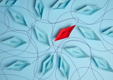 Paper boats on a blue background with paths of movement, representing the concept of individuality