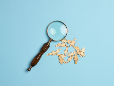 Wooden men and a magnifying glass on a blue background. Recruitment concept, search for talented and capable employees, career growth, flat layの写真素材