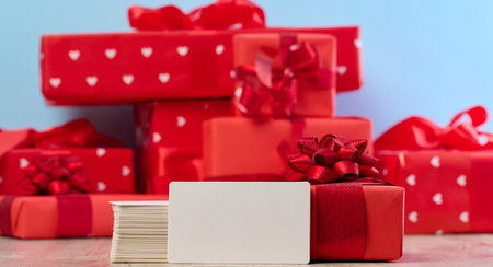 Stack of white paper business cards and gifts wrapped in red paper on a blue background