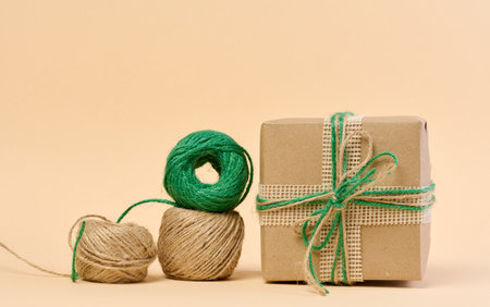 The box is packed in brown craft paper and tied with a rope on a beige background, gift