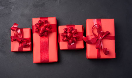 Boxes packed in red paper and tied with ribbon on a black background, gifts.の写真素材