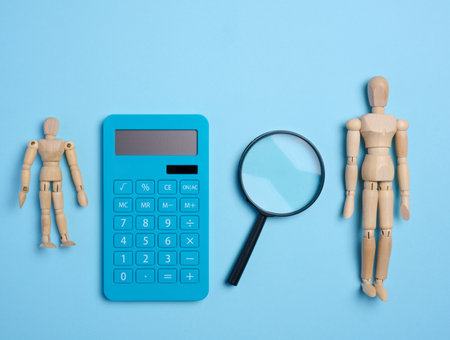 Wooden mannequin, magnifier and blue calculator. Concept of counting budget, taxの写真素材