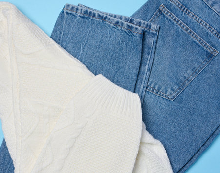 Blue jeans and white knitted sweater on a blue backgroundの写真素材