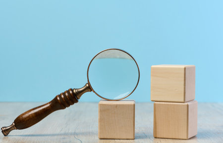 Wooden cubes and magnifying glass on blue backgroundの写真素材