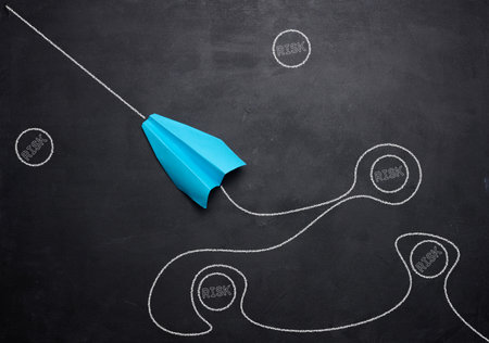A blue paper boat and a trajectory navigating around risky situations, symbolizing the concept of risk management and strategic navigationの写真素材