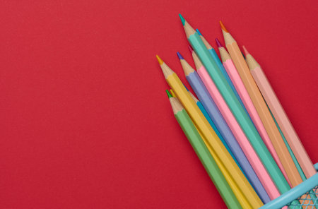 Multicolored wooden pencils on a red background, representing a vibrant and creative artistic conceptの写真素材
