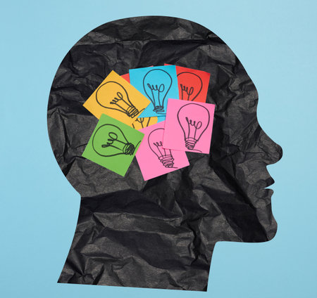 Silhouette of a human head and stickers with drawn electric lamps on a blue background, search for new ideas and solutionsの写真素材