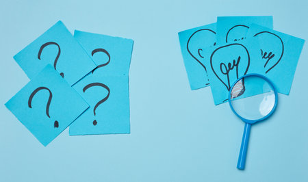 Drawn light bulbs on sheets of paper and a plastic magnifying glass, the concept of searching for new ideasの写真素材