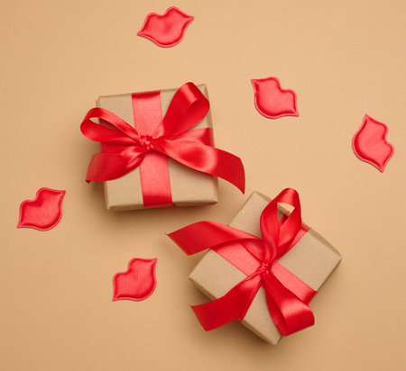 Gift box with red satin ribbon and bow on a brown background. Holiday backgroundの写真素材