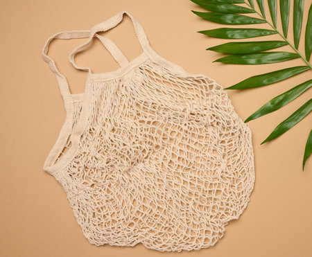 Textile grocery bag on brown background, top view
