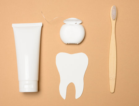 Toothbrush, toothpaste and paper tooth on a brown background, oral hygiene. View from aboveの写真素材