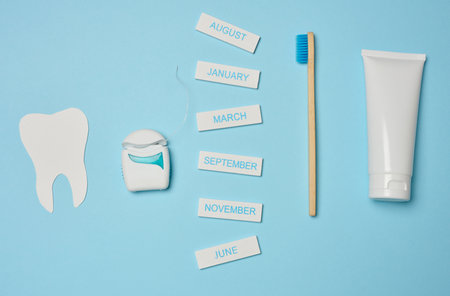 Tube with toothpaste, dental floss and toothbrush on a blue background, oral hygiene.
