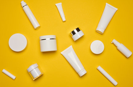 Various types of white plastic packaging, bottle, jar, tube on a yellow background. Container for...