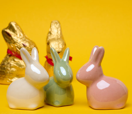 Ceramic decorative bunnies on a yellow background, festive Easter background