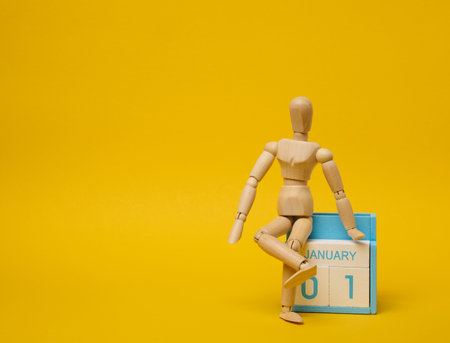Wooden puppet and calendar with the date the first of September on a yellow background. Copy spaceの写真素材