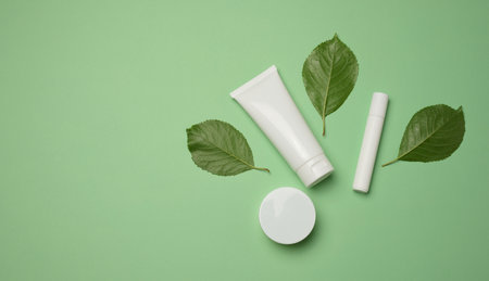 White plastic tubes, jars, and containers for cosmetic products on a green background, advertising and branding of productsの写真素材