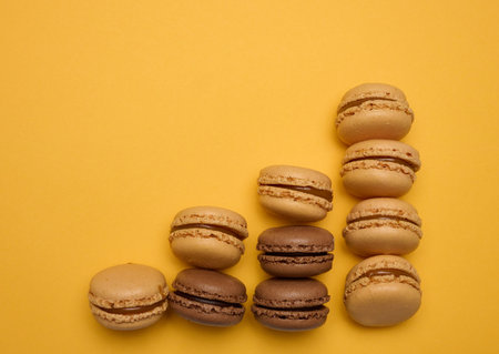 Chocolate macarons on a yellow background, dessert. Top viewの写真素材