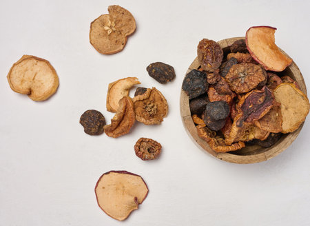 Dried apple pieces in a wooden round plate on a white table, top viewの写真素材