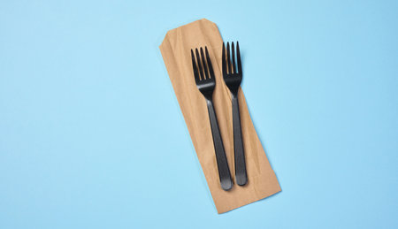 Plastic black forks on a blue background, disposable picnic items, top viewの写真素材