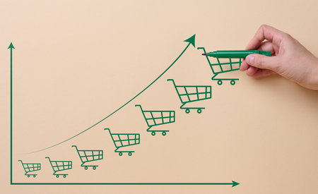 Graph drawn with green felt-tip pen with shopping carts on beige background, consumer growthの写真素材