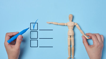 Concept of making decisions and completing tasks, wooden dummy in hand, other hand marking a checkbox on a list. Symbolizes control, choosing and completing tasks, decision makingの写真素材
