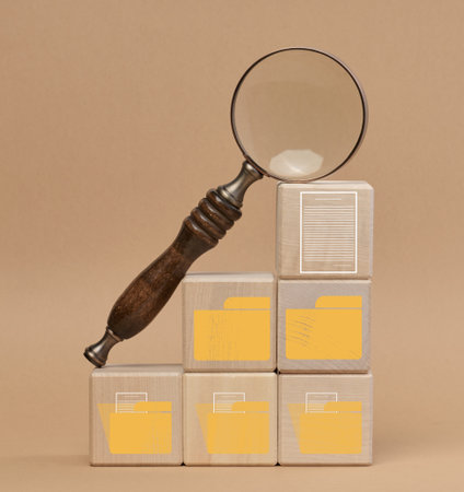 Magnifying glass mounted on wooden cubes with folder and document symbols, detailed file search and management processの写真素材