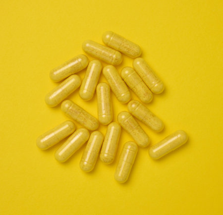 Yellow pills in a capsule on a yellow background, pain treatment