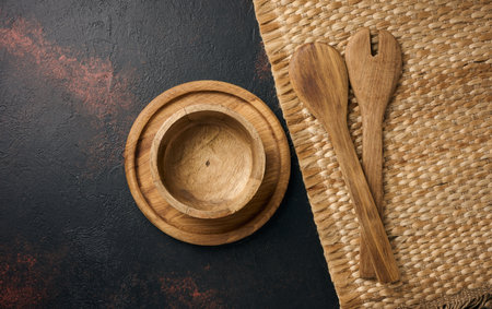 Empty wooden plate and wooden spoons on black background, top viewの写真素材