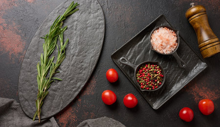 Culinary composition with kitchen utensils and spices, Himalayan salt, colorful peppercorns, fresh rosemary on the table. Top viewの写真素材