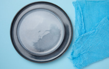 Round ceramic empty blue plates and blue kitchen towel, top viewの写真素材