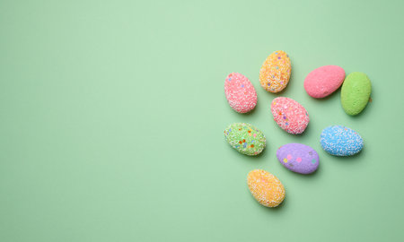 Multicolored decorative Easter eggs on green background, top view. Copy space