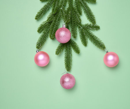 Shiny pink balls and green fir branches on green background, Christmas backgroundの写真素材