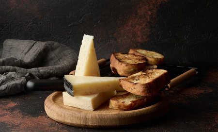 Triangular pieces of cheese and fried ciabatta slices on a wooden boardの写真素材