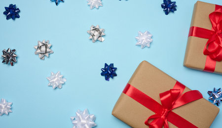 Gift box with red satin ribbon and bow on a blue background. Holiday backgroundの写真素材