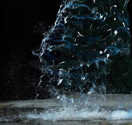 Splashes of clean transparent water on asphalt, black backgroundの写真素材