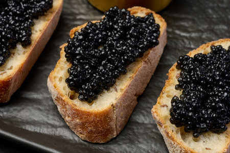 Sandwich with baguette and black caviar on a black board, close upの写真素材