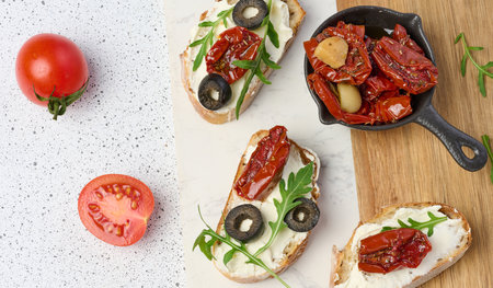 Sandwich with cream cheese and sun-dried tomato slices on white table, top viewの写真素材