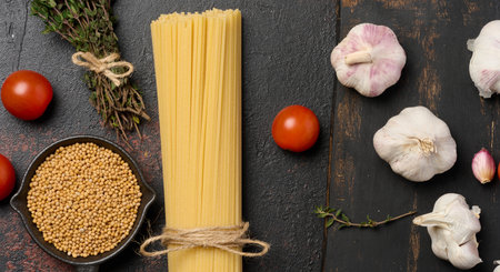 Spaghetti, tomatoes, aromatic oil and fresh herbs on the table, top viewの写真素材