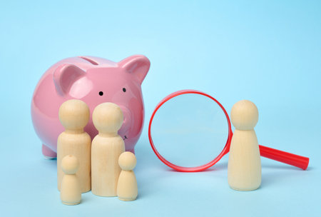 Wooden figurines of a family on the background of a ceramic piggy bank, financial literacy conceptの写真素材